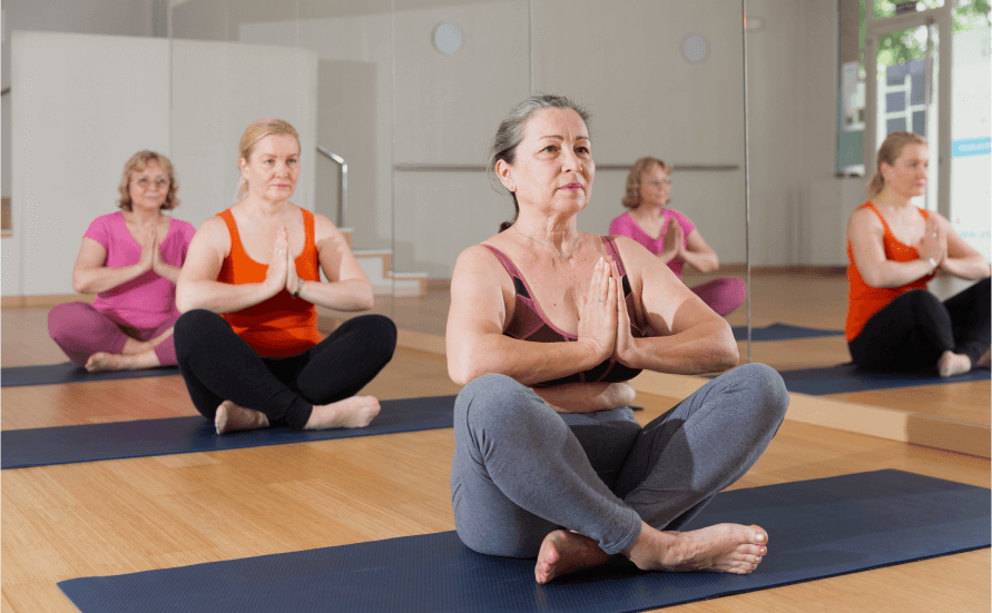 Group of older women doing yoga on a studio